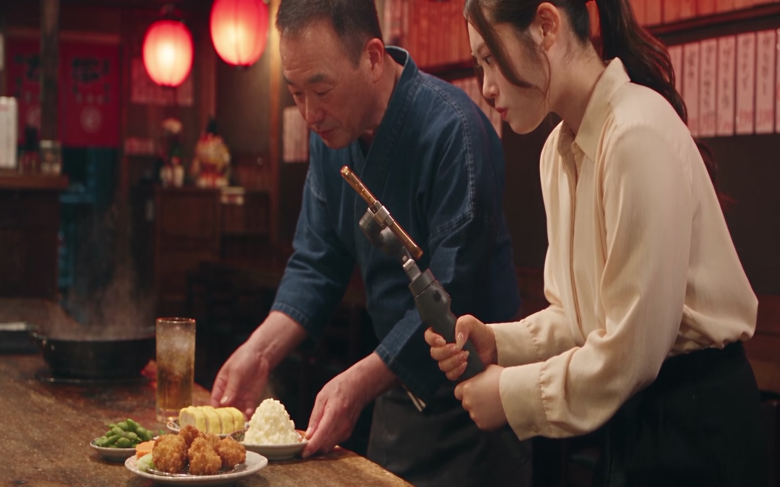 店主と一緒に料理を整え、女性スタッフが縦動画を撮影する支援のイメージ